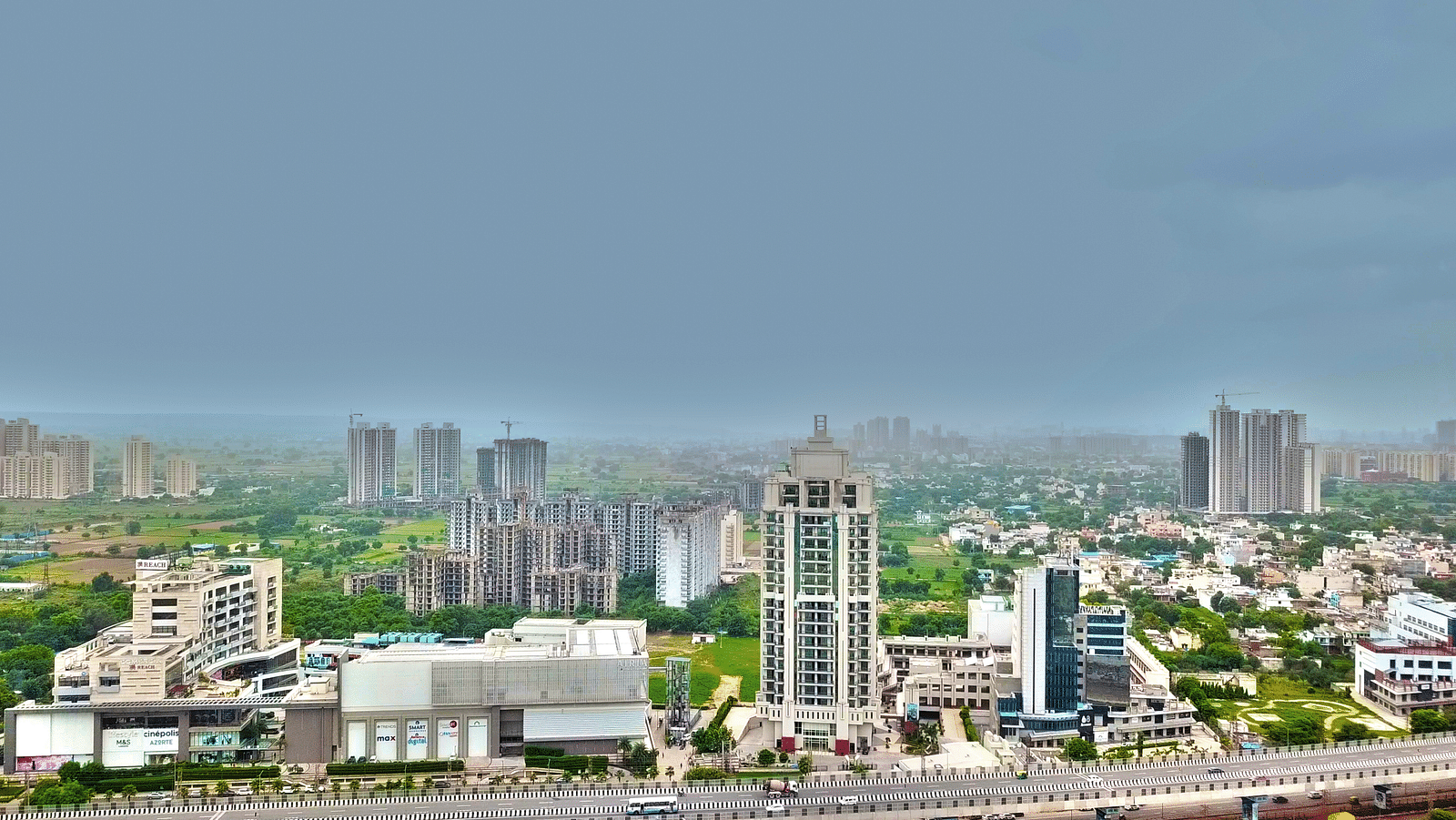 Bird's eye view of Rhythm Gurugram with other buildings and trees next to it 