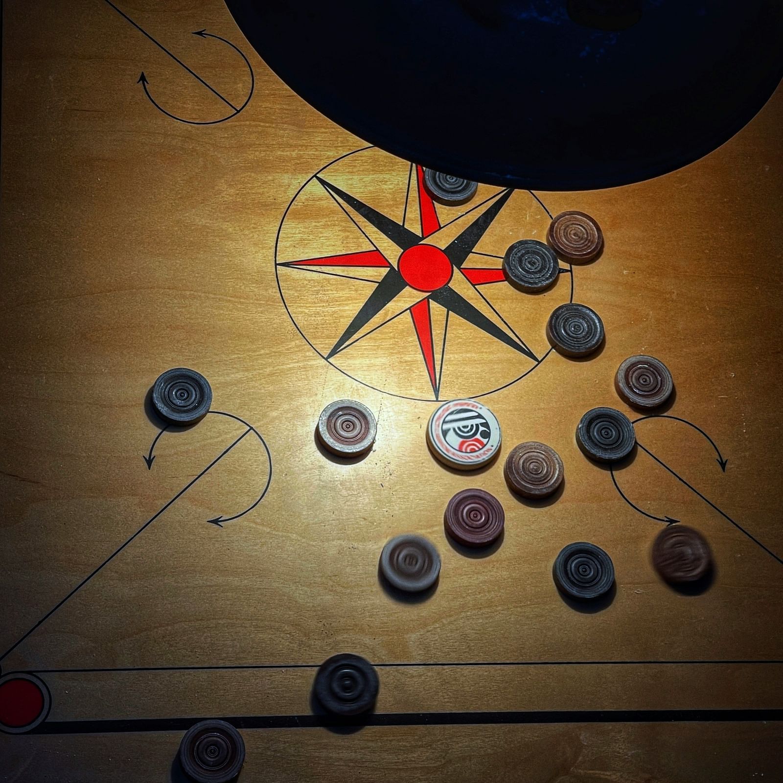 coins scattered around on a carrom board