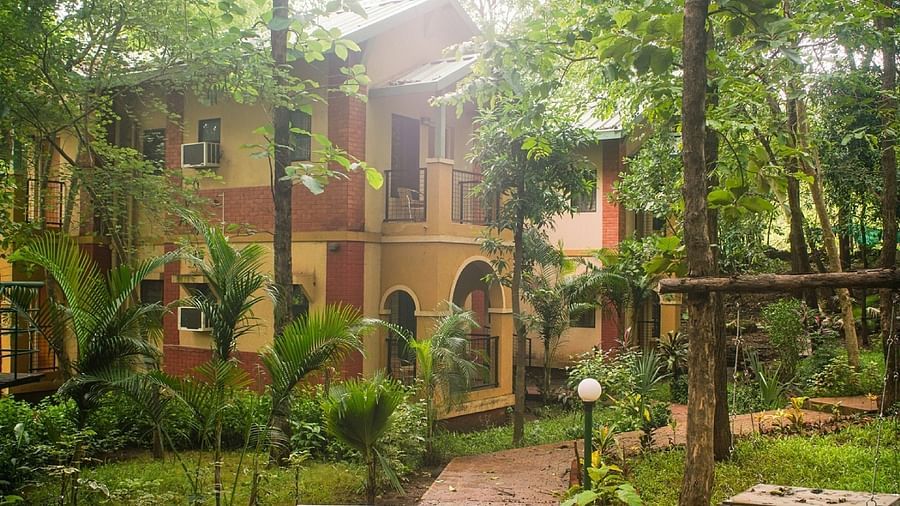 Yellow two-story building with red accents, surrounded by trees at Nature Trails Sajan.