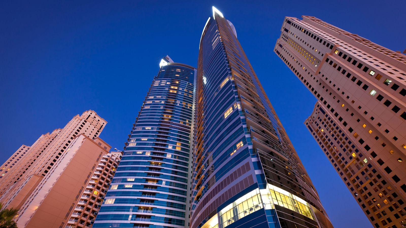 few skyscrapers as seen from below soaring high with the night sky in the background - Rhythm Gurugram