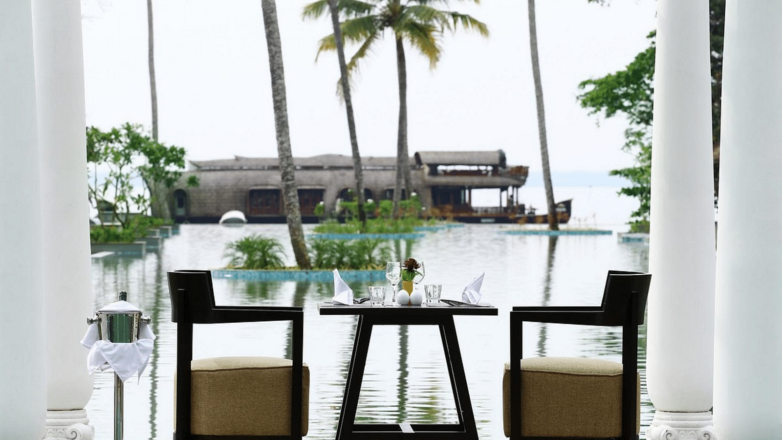 Seating arrangement in front of the pool with a coconut trees in view - Rhythm Kumarakom.