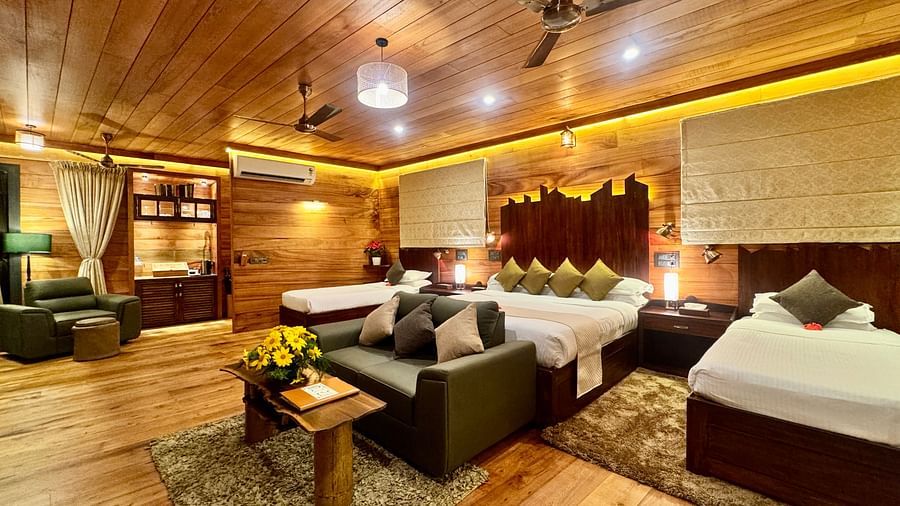 A warm room featuring a double bed, armchairs, a small table, and wooden panelling - BluSalzz Collection - Tranquil Resort, Wayanad