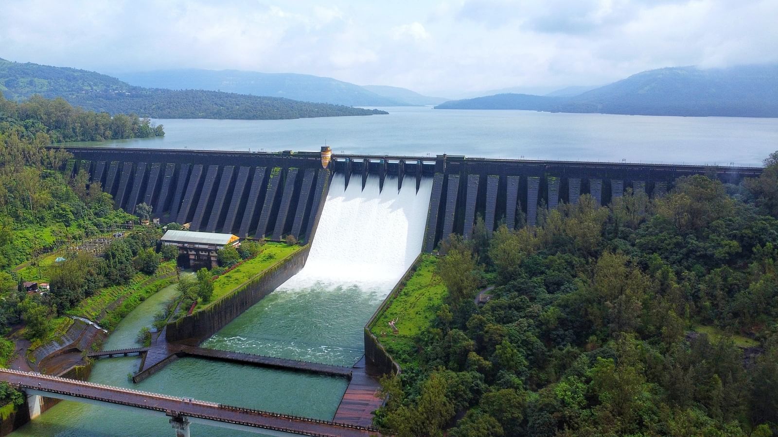 The Konya dam releasing water surrounded by forested hills