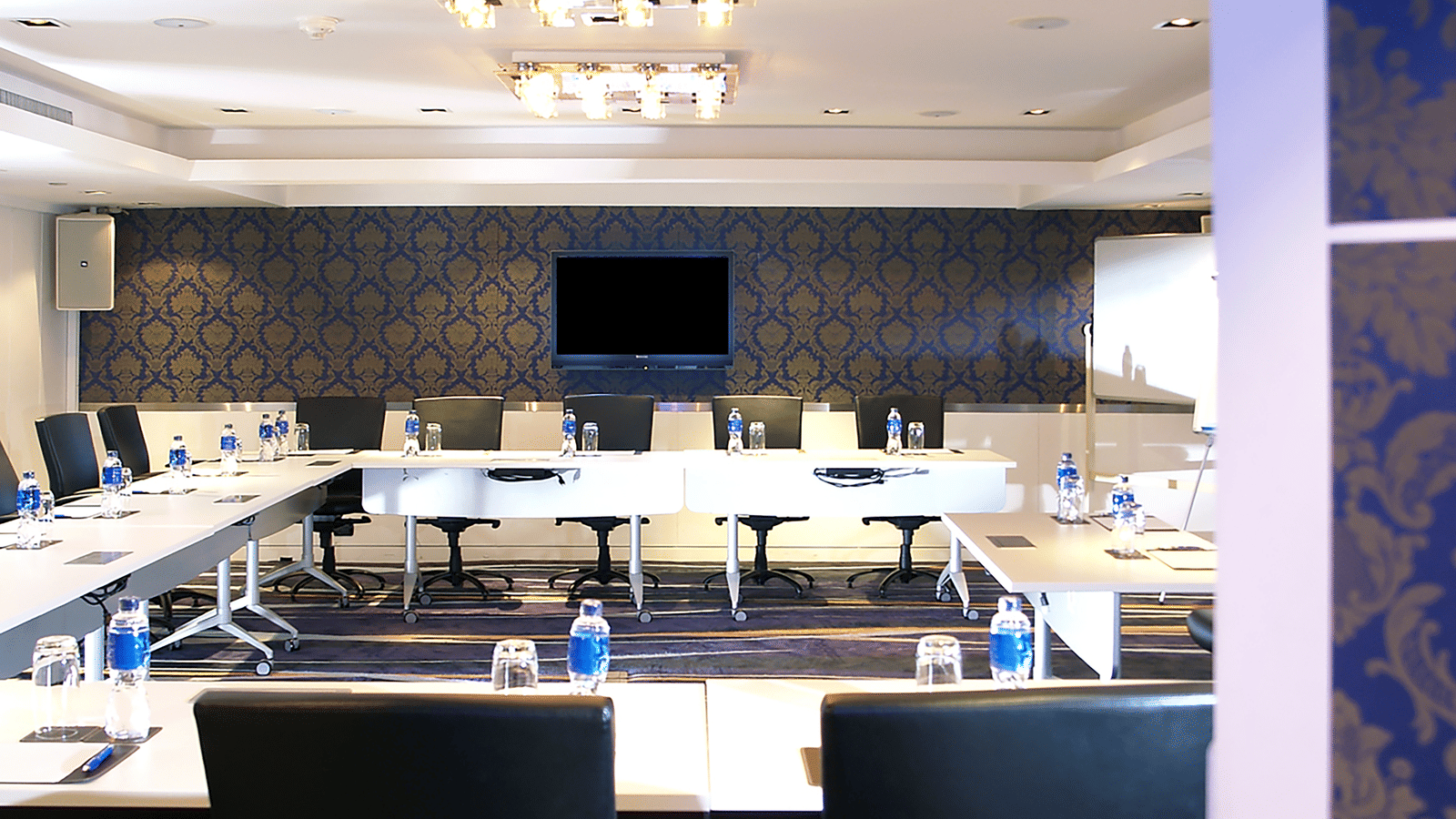 Modern meeting room in Bangkok with U-shaped seating arrangement, executive chairs, elegant lighting, and a large presentation screen set up for corporate meetings or business events | Night Hotel Bangkok