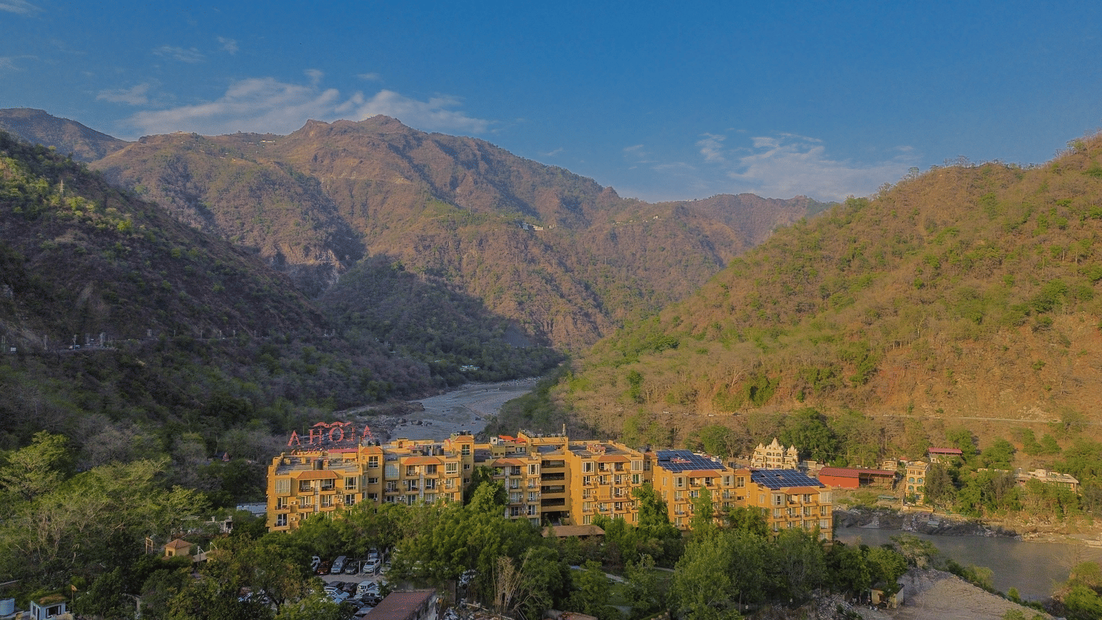 A scenic view of Perfectstayz Value Alpine Retreat, Rishikesh nestled among lush green hills.