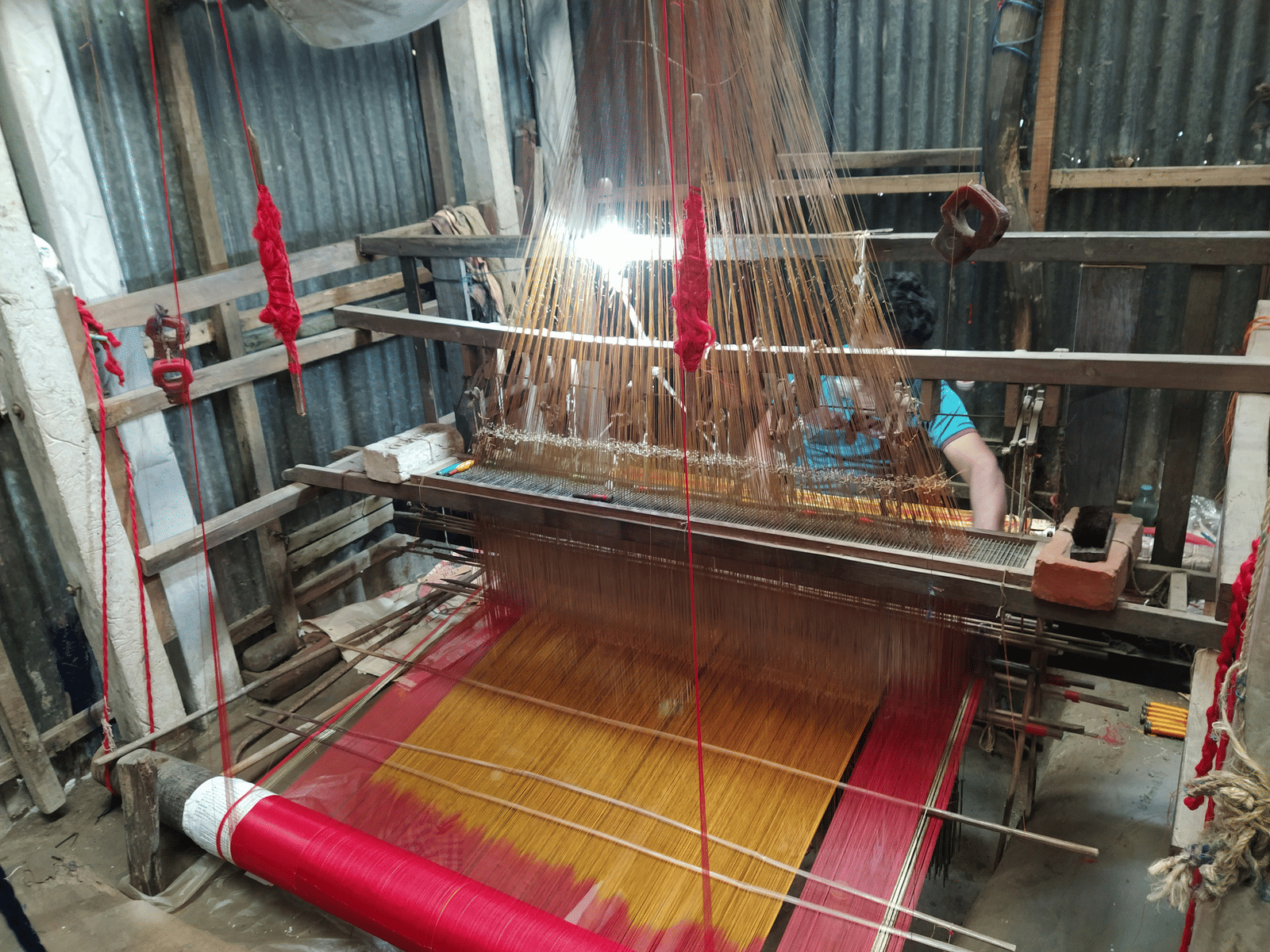 A person using a hand weaving machine to make a garment.