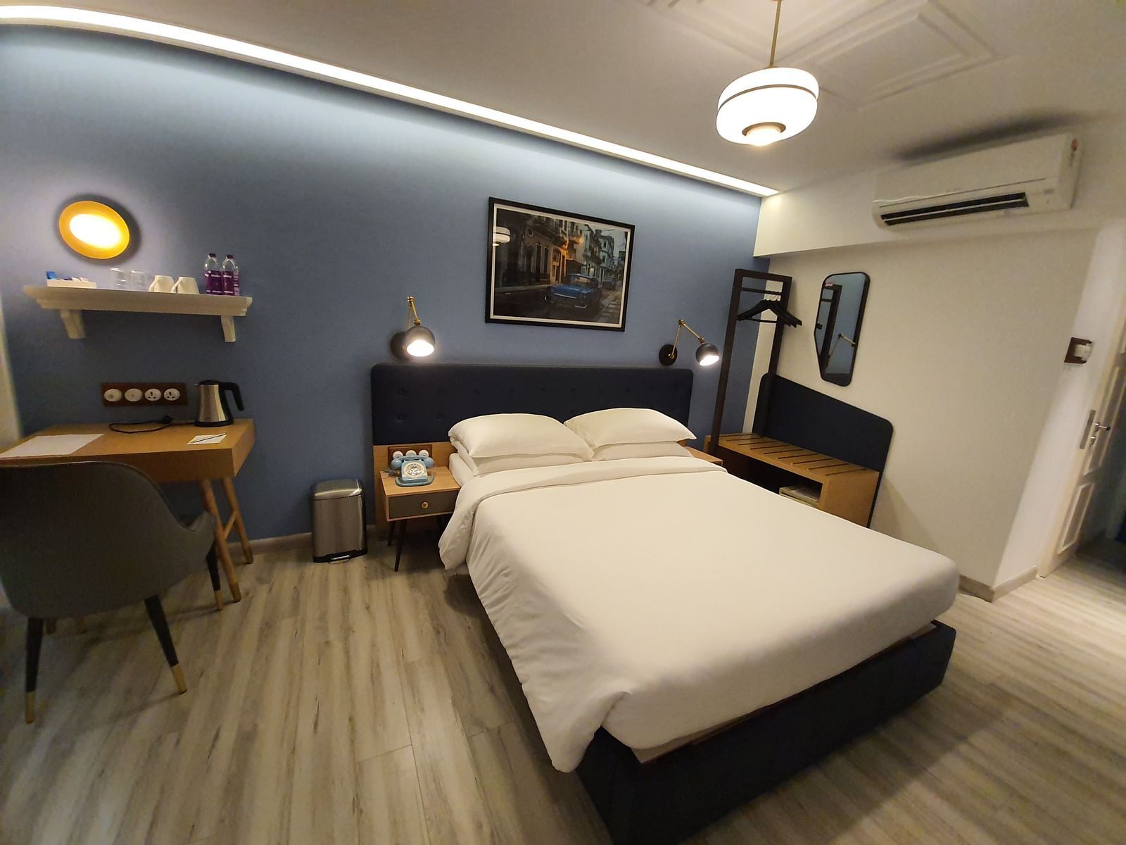 Deluxe Room at T24 Retro Vile Parle East featuring a double size bed, bedside table with telephone, a work desk and chair, an AC, and more.