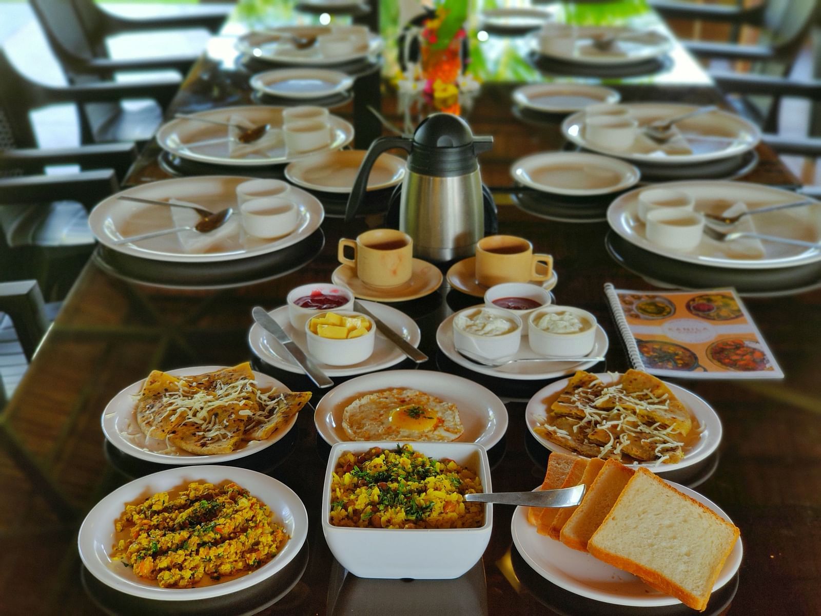 A wooden table is covered with plates of various appetisers. There are french fries, bread, and coffee | The Kanila Resort