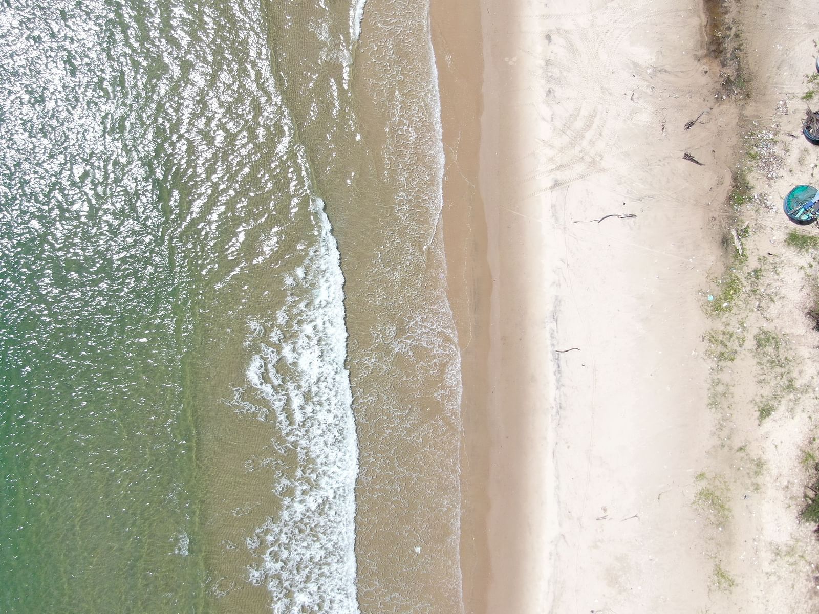 A top down aerial view of a beach on a sunny day with waves overlapping the shore - WoCAL Retreat Ke Ga