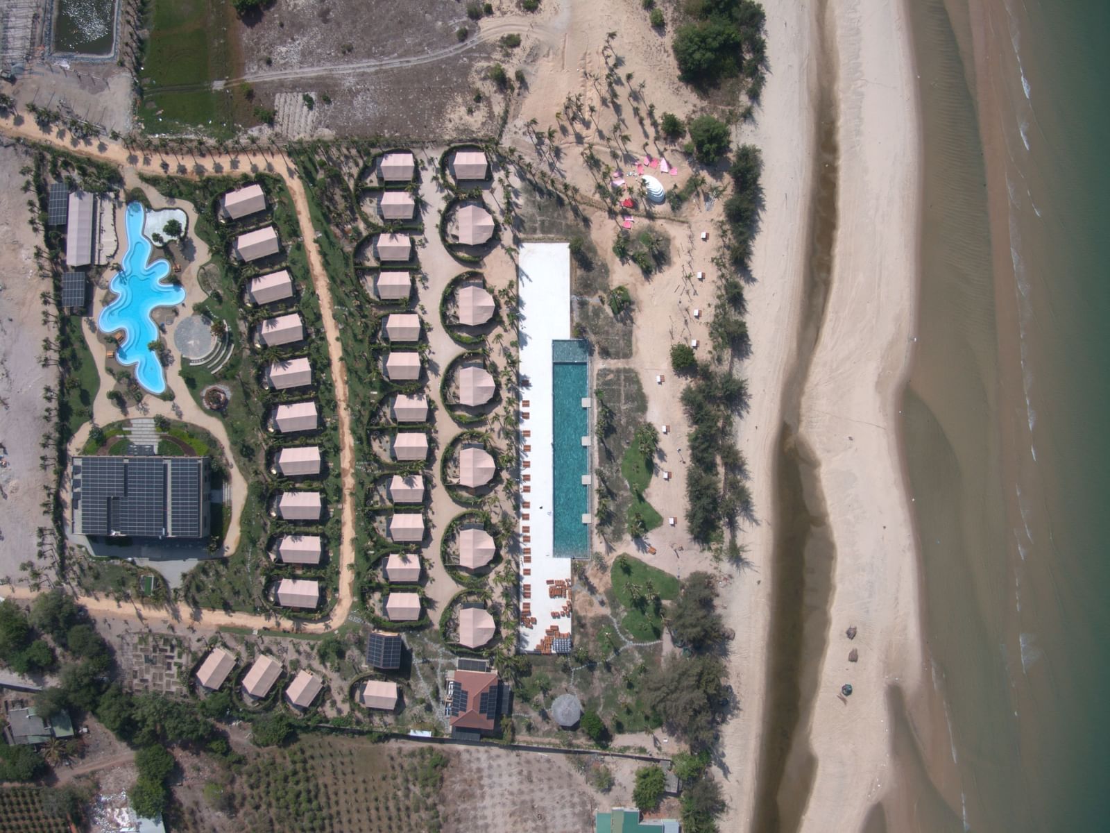 A top view of a WoCAL Retreat Ke Ga resort lit warmly in the evening with the beach on the right.