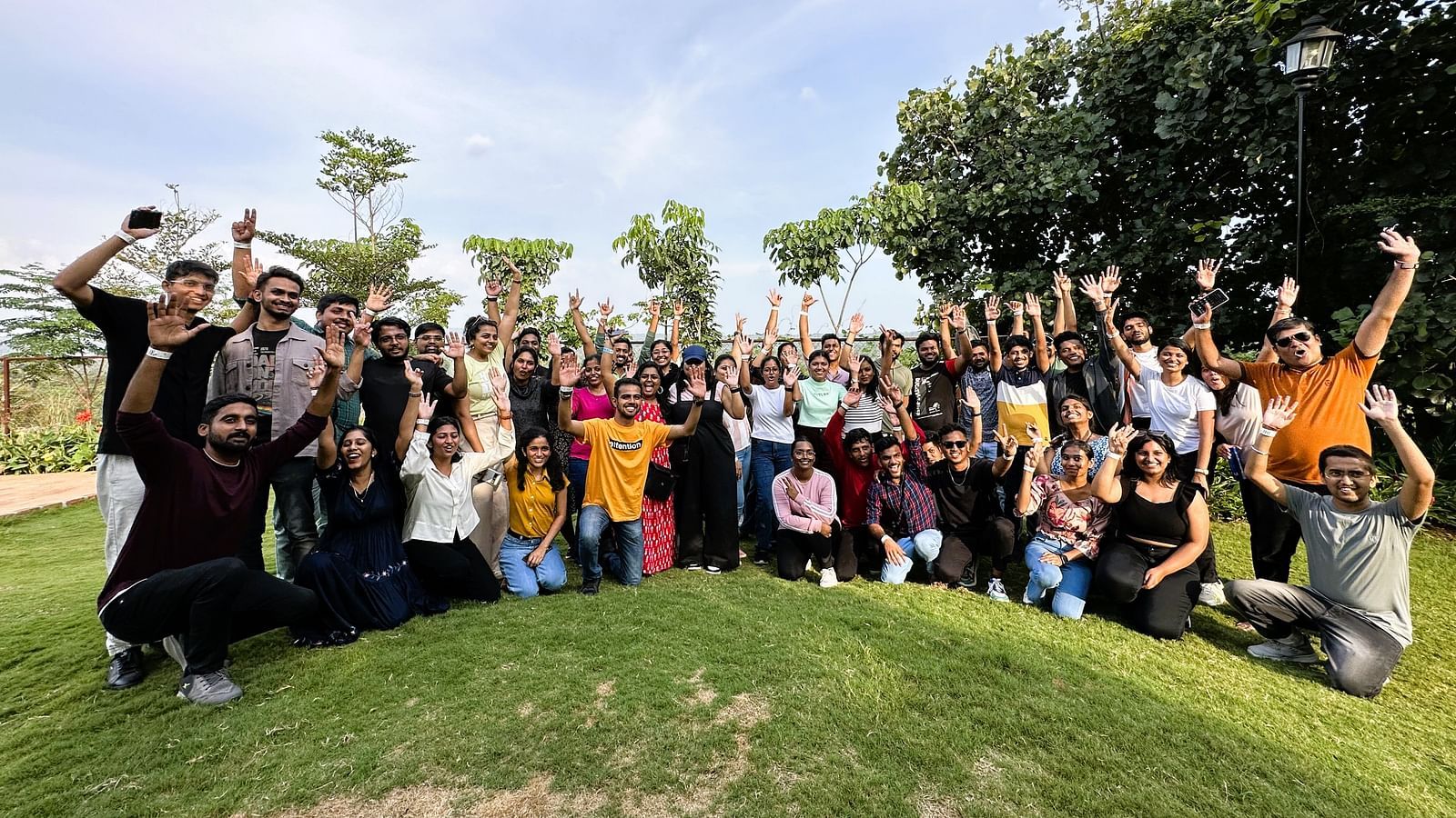 A corporate group at Ravishing Retreat smiling and raising their hands while posing for a photo