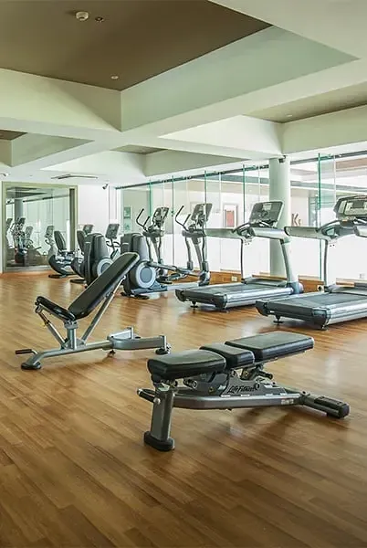Gym with treadmills, cross trainers and other exercise equipment on wooden flooring at Karma Chalets.