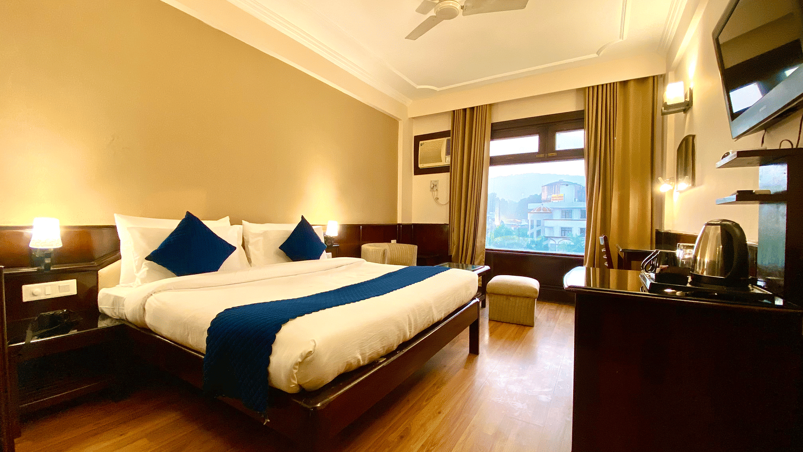 An overview of the premium room with a ceiling fan and windows covered by curtains at DLS Park Grace, Haridwar - One of the best Hotel Wedding Venues