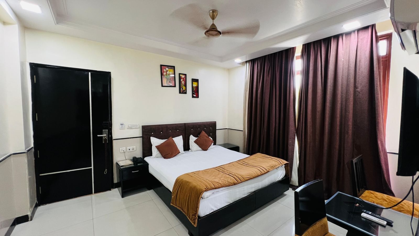 Well-appointed hotel room with a bed, small desk, and wall-mounted decor | Deluxe Room | Hotel Aadhar