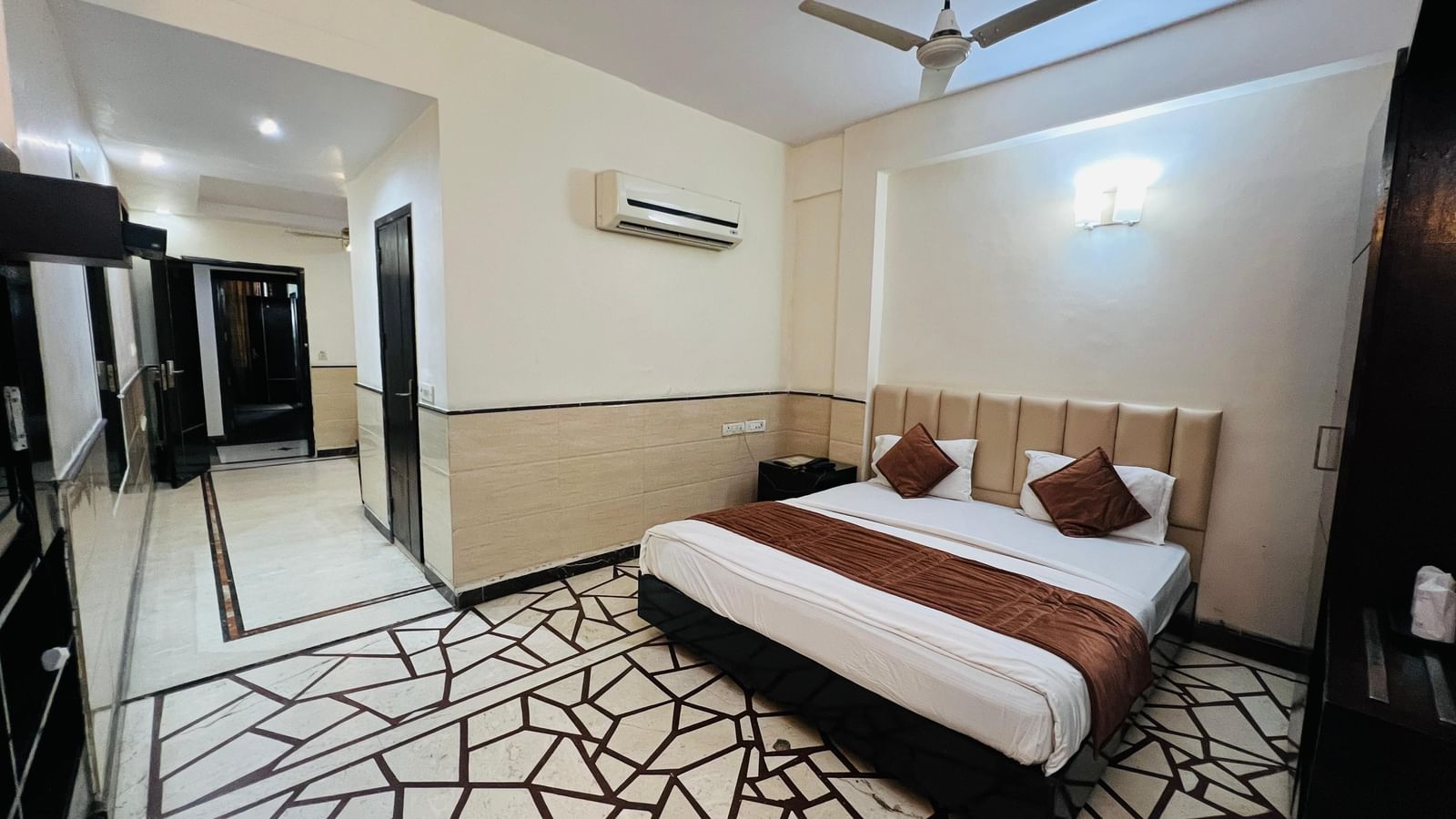 A well-appointed hotel suite featuring a comfortable bed with brown and white bedding, and a spacious layout. | Suite | Hotel Aadhar