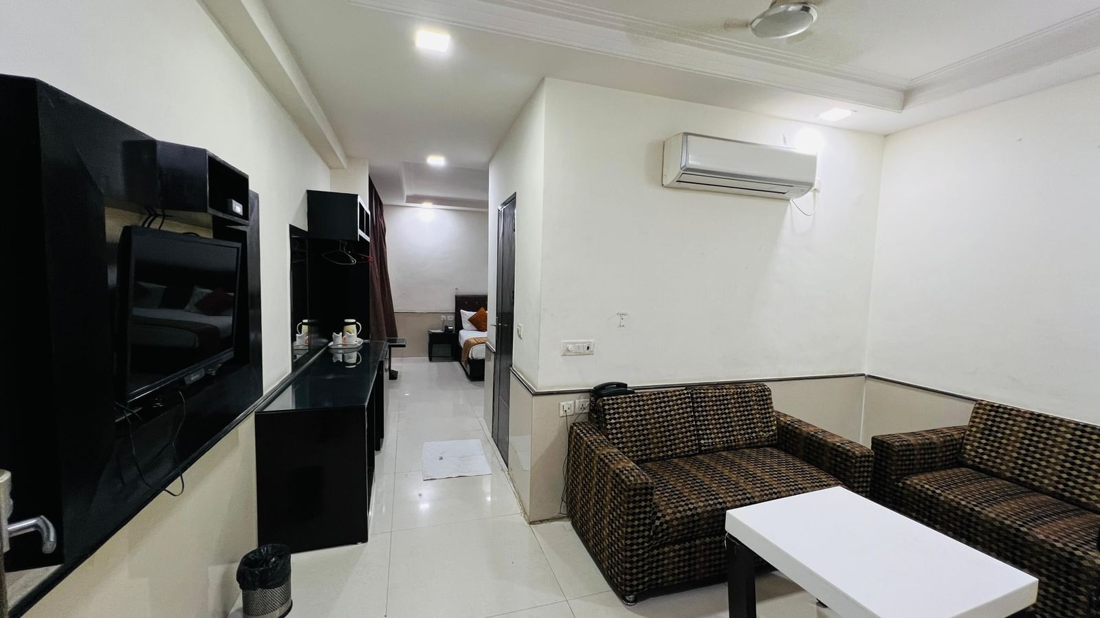 A cozy hotel suite with a brown L-shaped sofa and a white coffee table, perfect for relaxation and casual meetings. | Suite | Hotel Aadhar