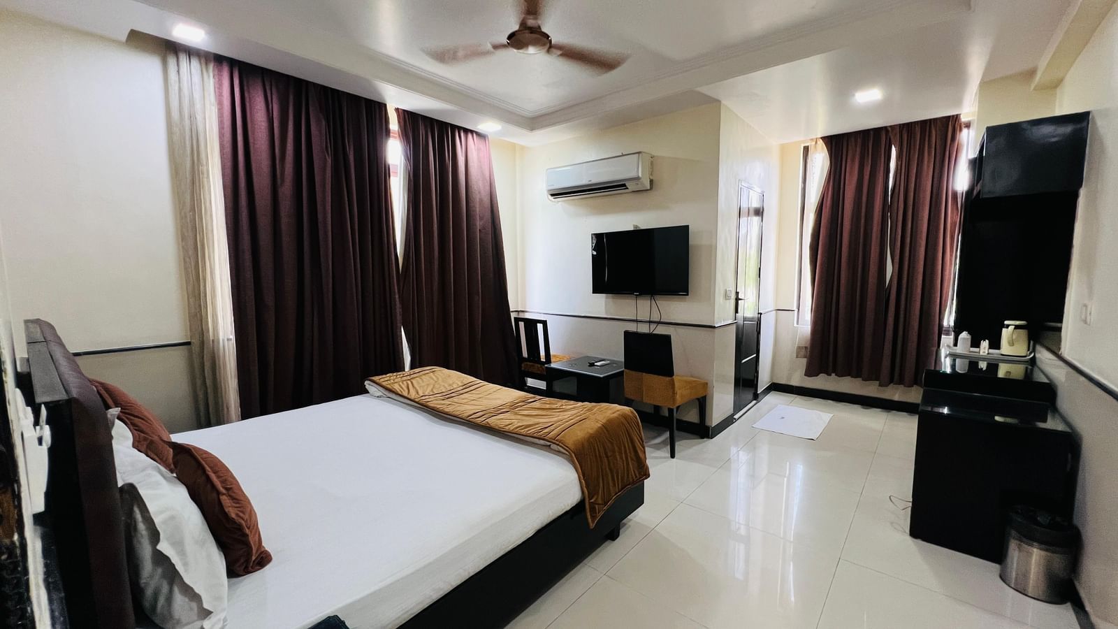 A comfortable hotel suite with a brown sofa, a white coffee table, and a blue abstract painting, offering a cozy atmosphere. | Suite | Hotel Aadhar