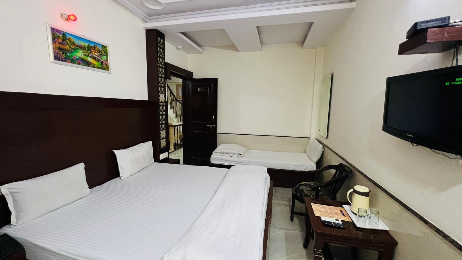 A well-furnished hotel room featuring a large bed, a sofa, and a TV, providing ample space and amenities for a relaxing stay. | Super Deluxe Room | Hotel City Palace DX