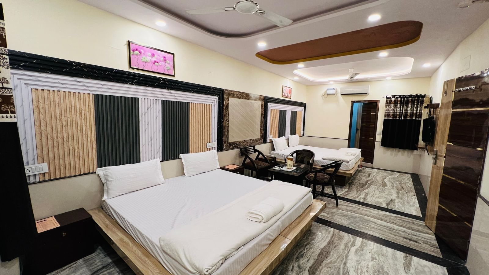 A hotel room with two beds, a dining table, and contemporary furnishings, offering a comfortable and practical space. | Family Room | Hotel City Palace DX
