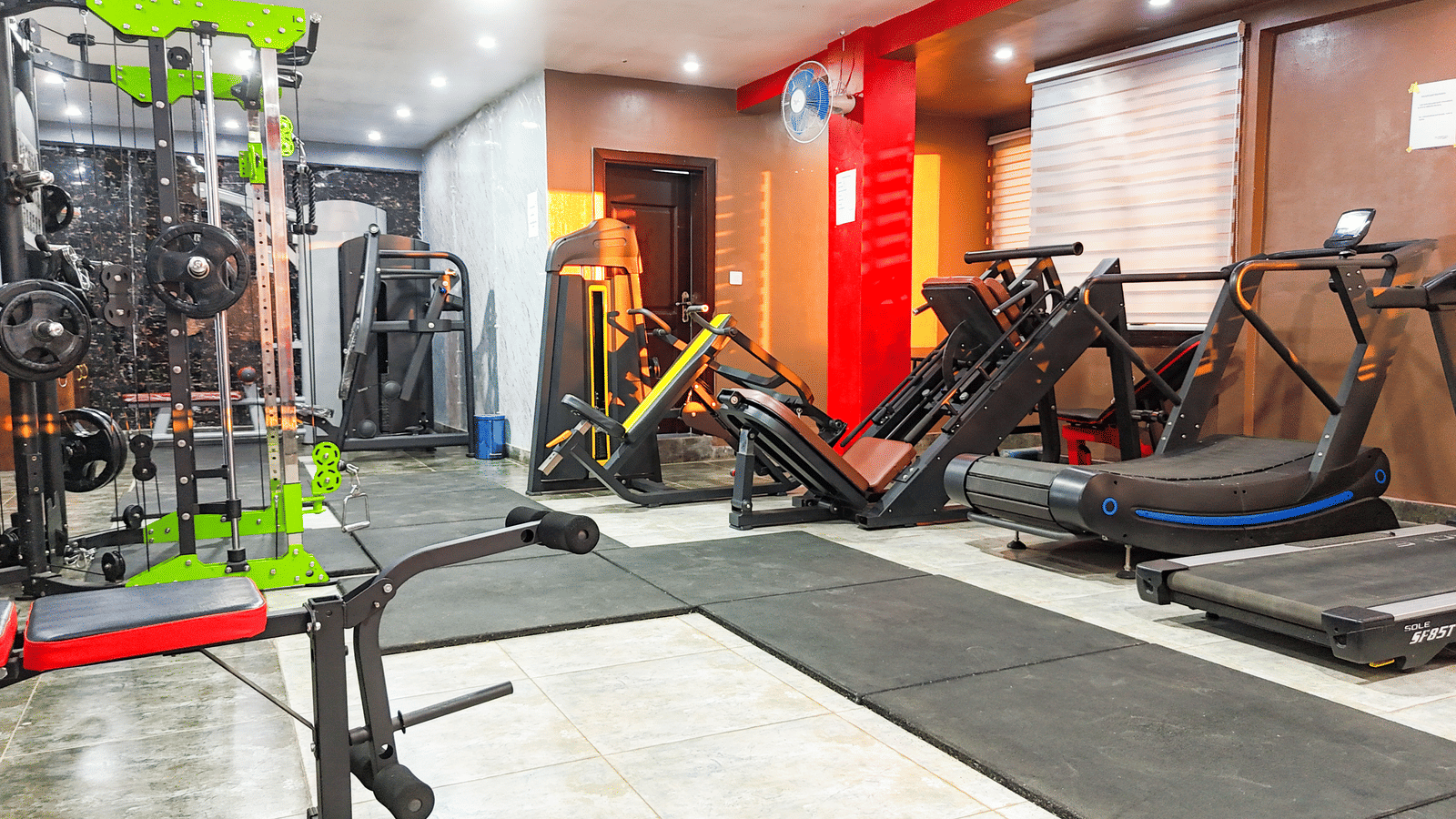 Interior view of a gym with various cardio and weight machines, including a treadmill and cycling machine - Luffu Club