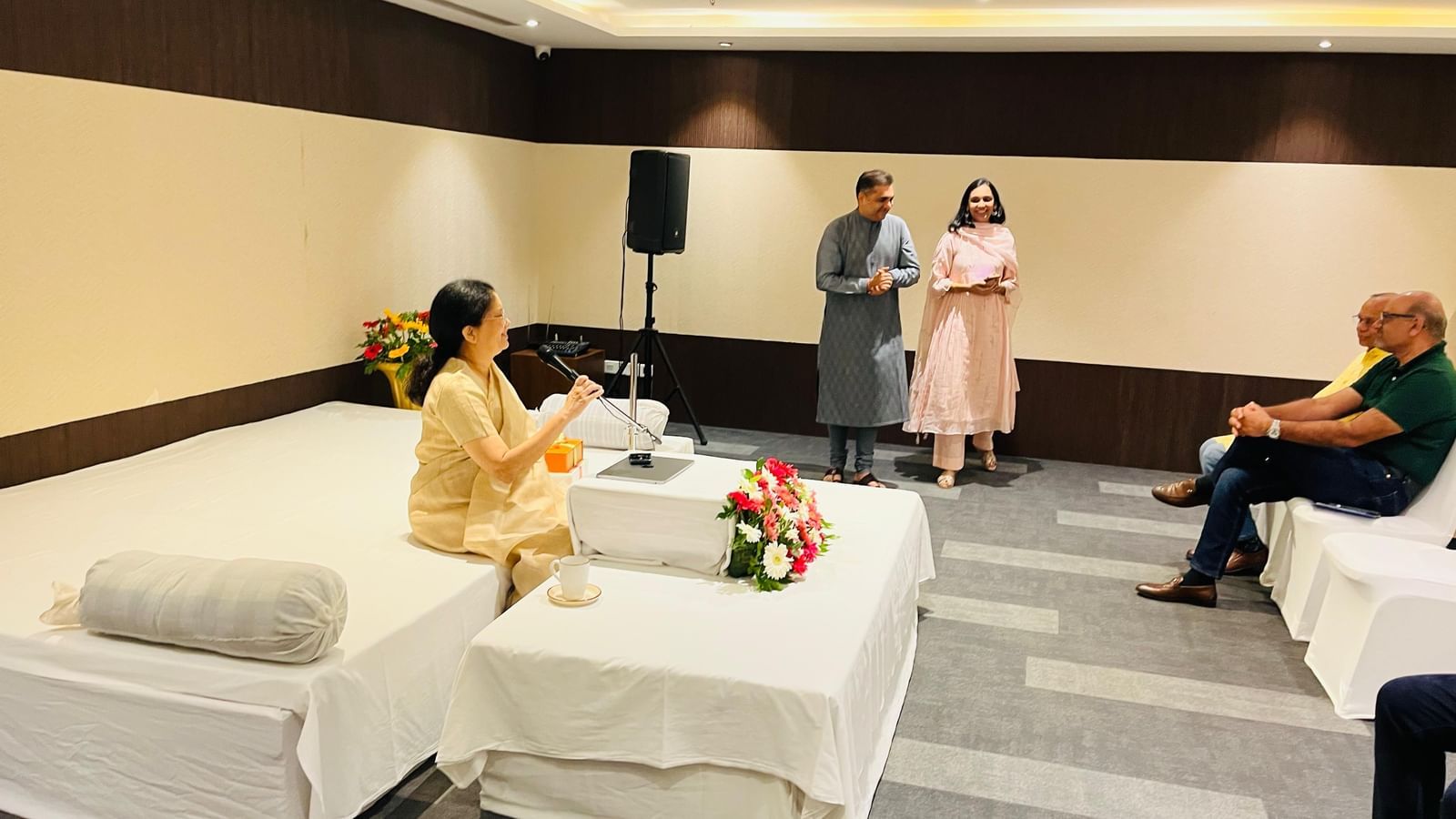 A event at Rhythm Hospitality with a guest speaker interacting with the audience, while hosts stand nearby.