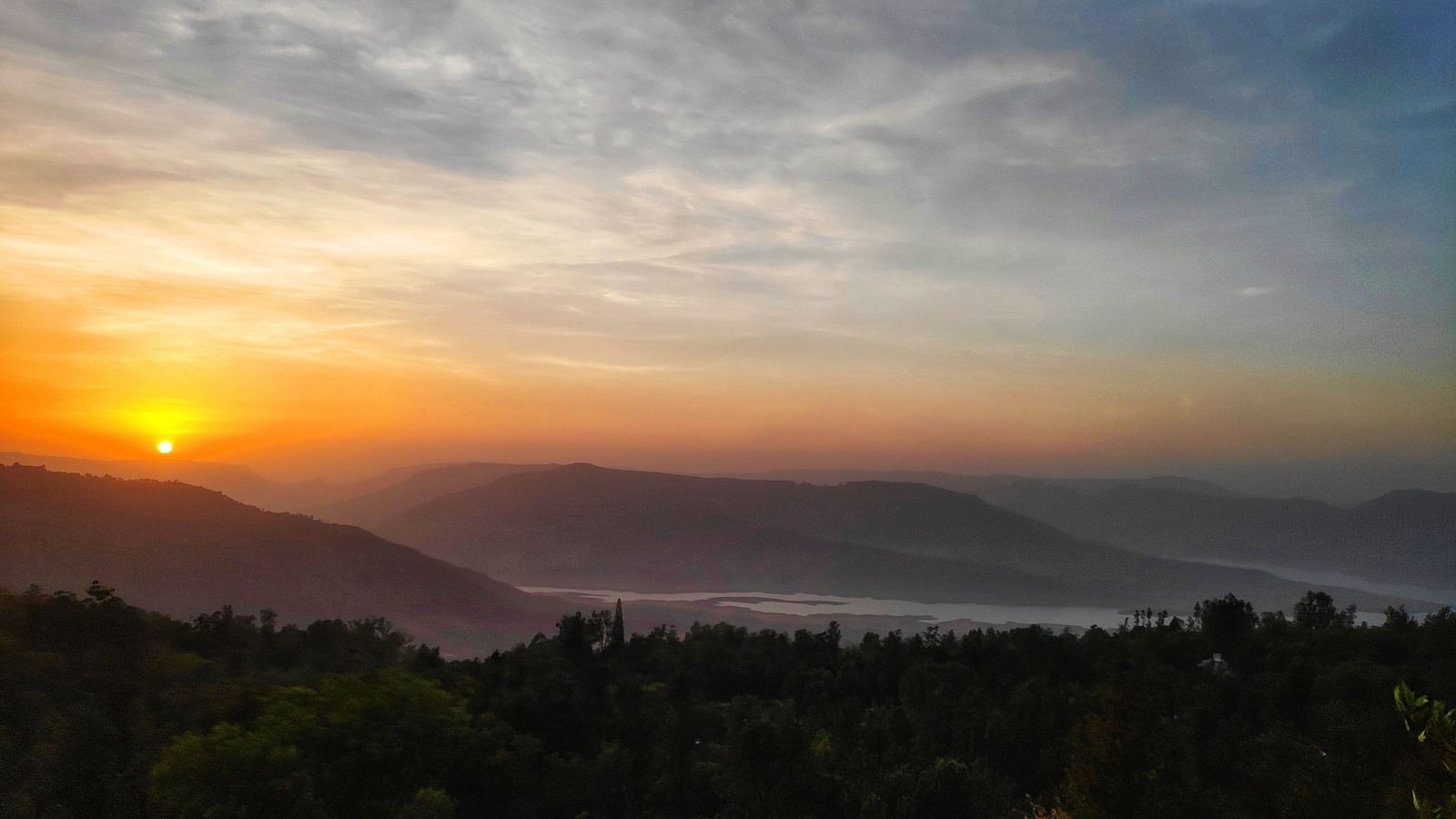 an image of a view of mountain valleys with a sunset in the background