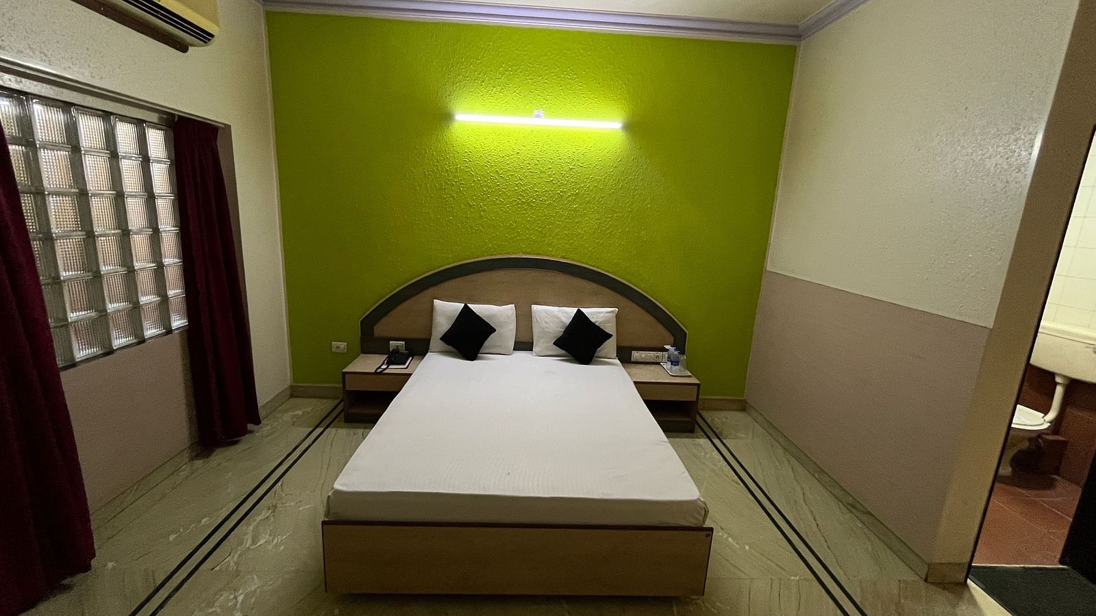 image of the Standard Room featuring a double bed against a green coloured wall at The Grand Krishna Rooms in Bengaluru