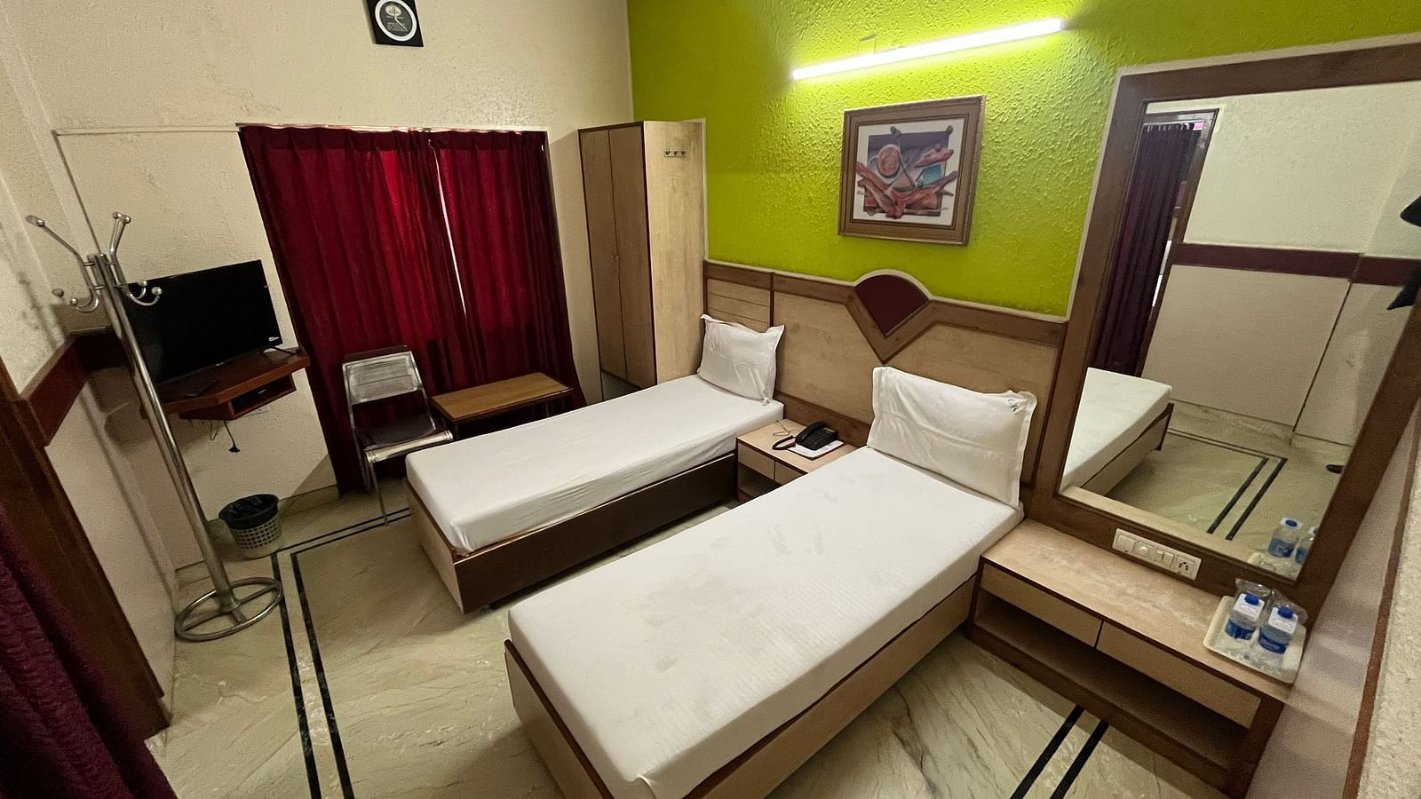 image of the superior room featuring twin beds at grand krishna rooms in bengaluru with a green coloured wall in the back