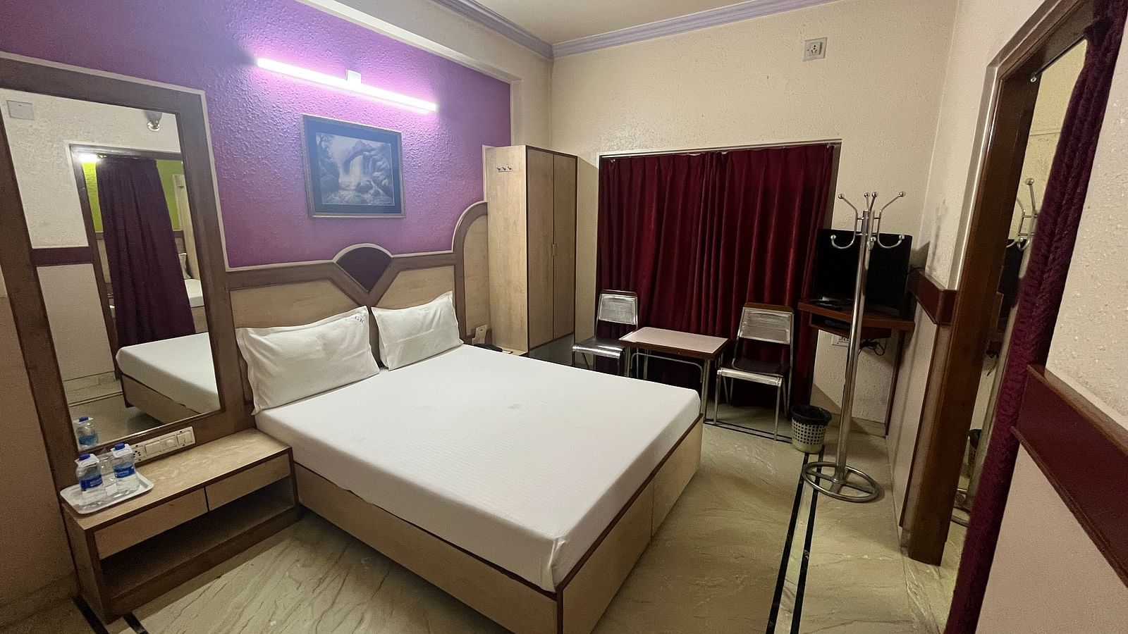 image of the superior room featuring a double bed against a lavender coloured wall in the background at grand krishna rooms in bengaluru