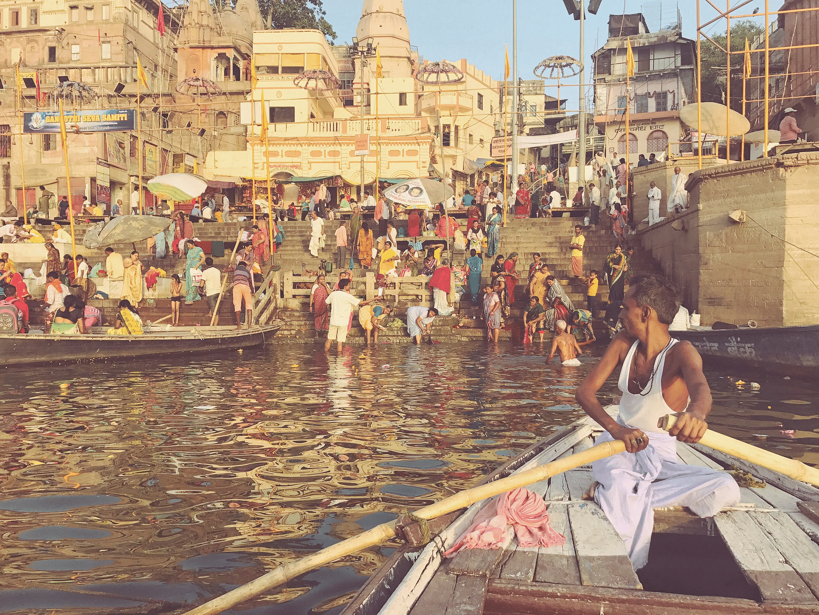 Boats on the Ganges River with people gathered at the ghats in Varanasi.