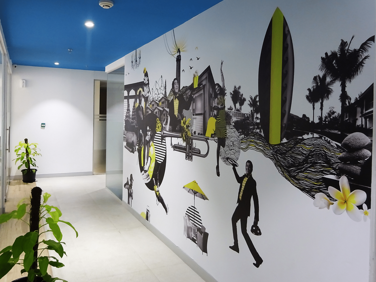 View of a corridor with painted illutration of the wall, two indoor plants and a blue roof.