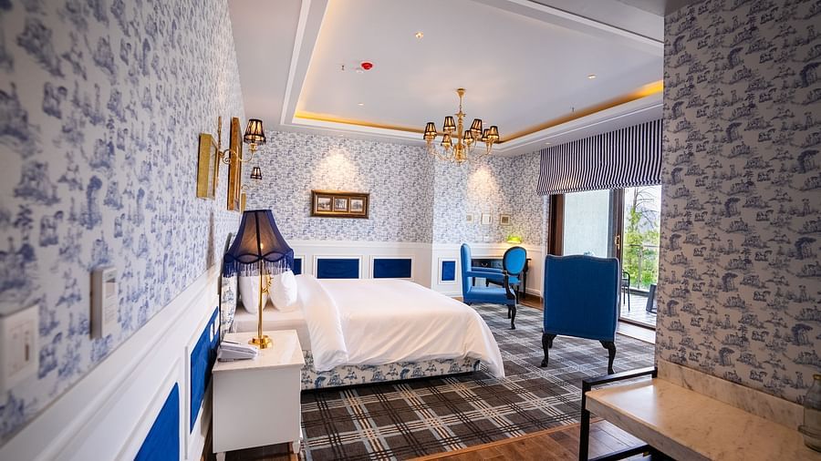 alt-text A hotel room with a large bed and comfy blue chairs  - The Manor Luxury Hotel, Shimla
