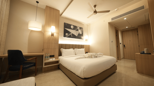 Premium Room with a king-sized bed, wooden furnishings, comfortable seating, art on the wall, and soft neutral lighting.