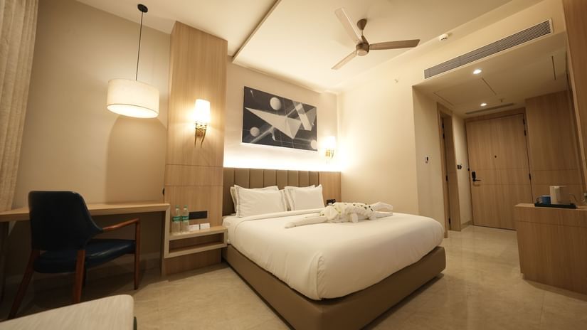 Premium Room with a king-sized bed, wooden furnishings, comfortable seating, art on the wall, and soft neutral lighting.