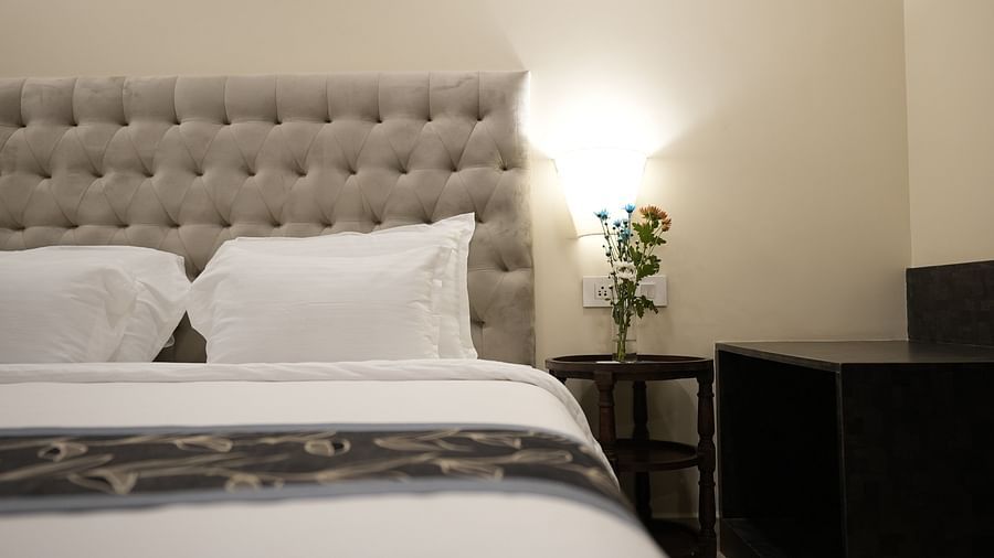 Close-up of a bed with plush pillows and a flower vase on the bedside table at The Verda de Miranda Resort.