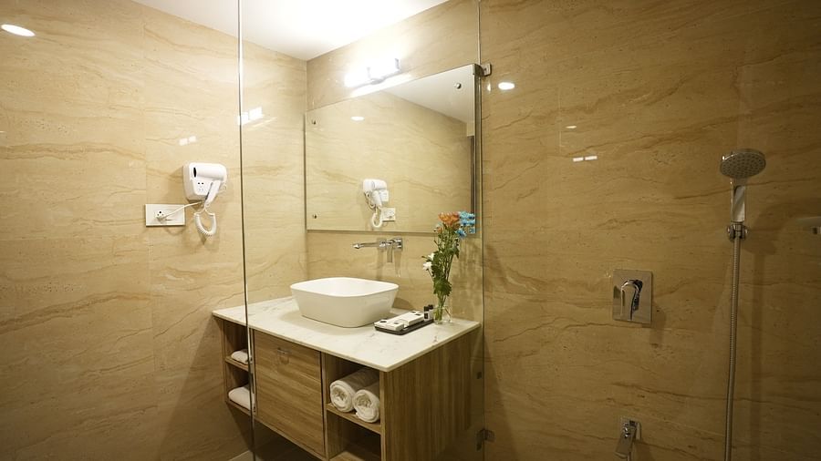 A stylish bathroom with beige tiles, a glass shower enclosure, and a contemporary washbasin – The Verda de Miranda Resort.
