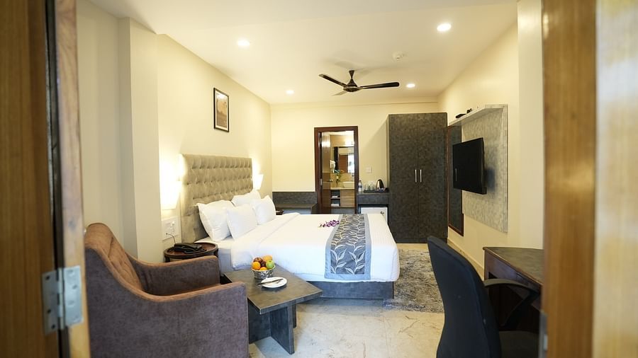 A well-lit modern bedroom with twin beds, a plush armchair, and a wall-mounted TV – The Verda de Miranda Resort.