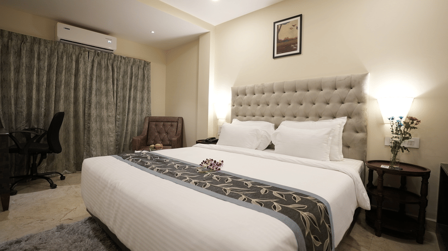 Modern hotel room with a work desk, large bed, and grey curtains at The Verda de Miranda Resort.
