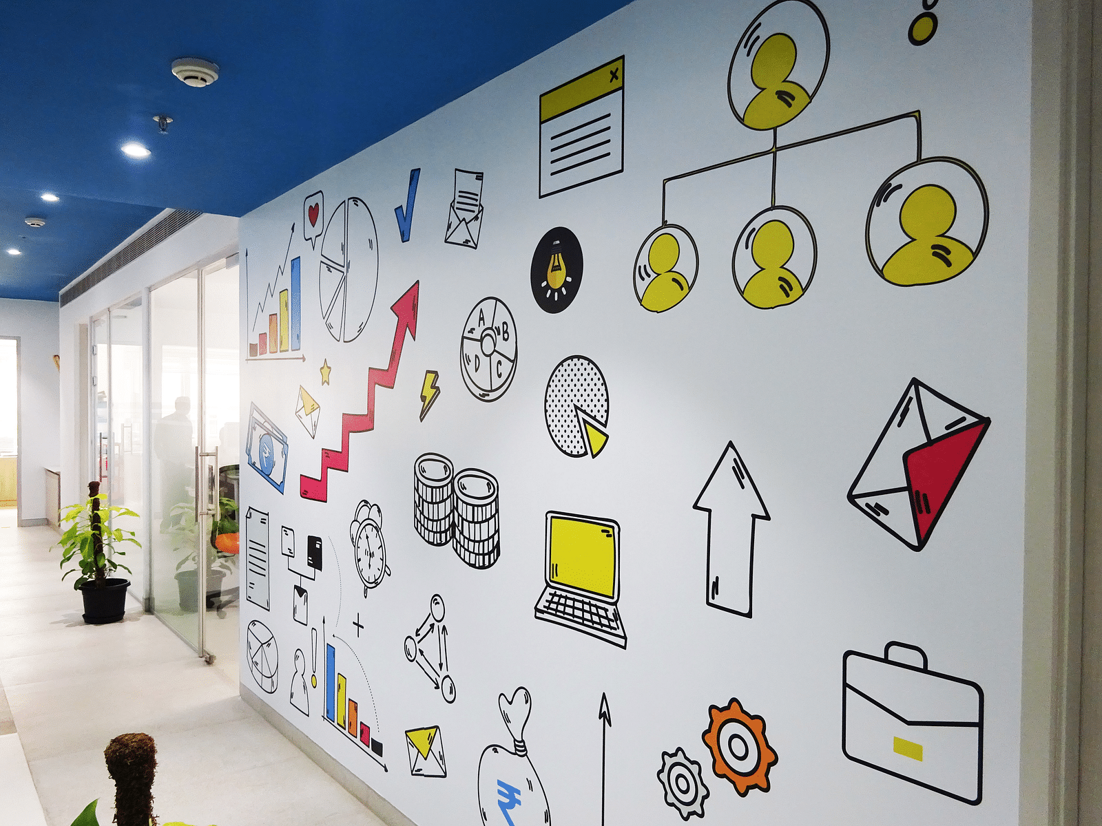 View of an office wall with fun illutrations on white colour and a blue painted roof.