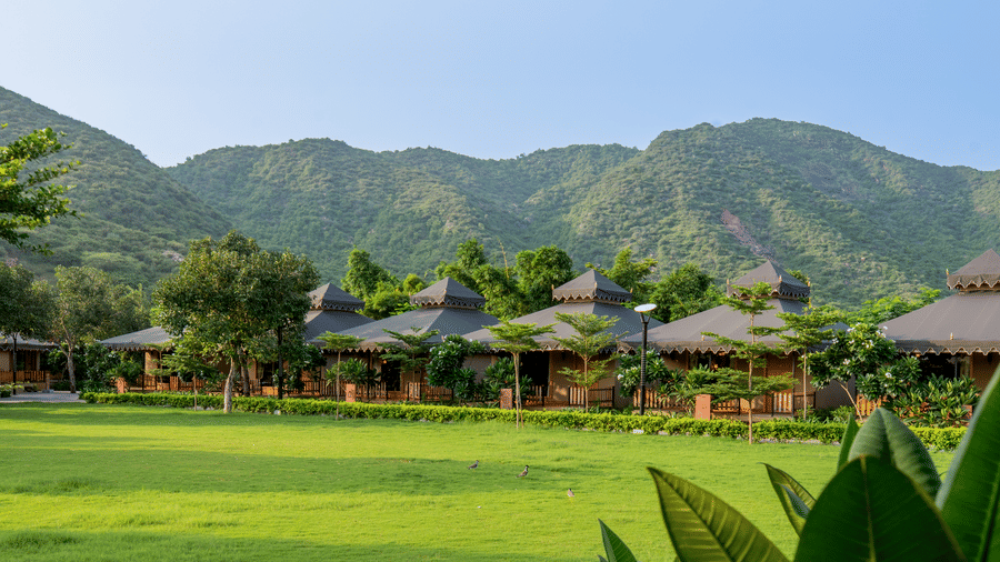 The view of accommodation tents at Pushkara Resort & Spa, Ajmer, with Aravalli Hills seen from the lawn.