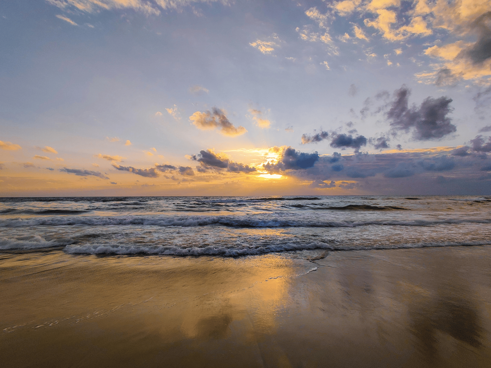 A serene sunset at the beach, with vibrant colours reflecting on the water near The Raintree, St. Mary's Road