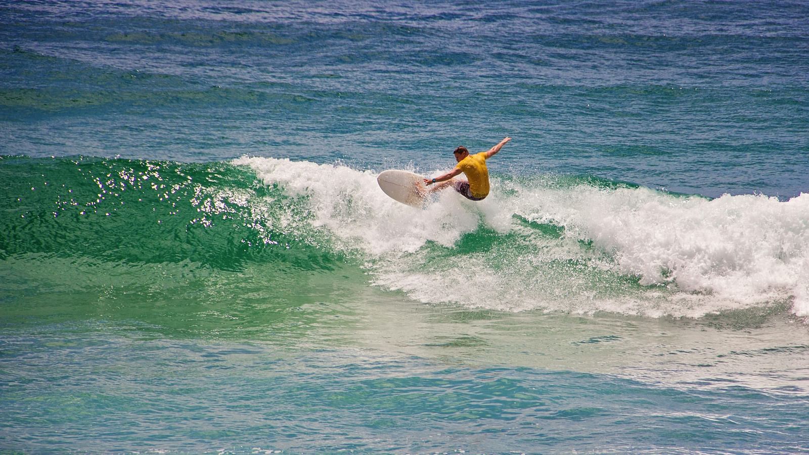 Man in yellow shirt surfing.