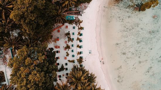 an aerial view of a white sandy beach with loungers set up to rest - best places to visit in Port Blair 