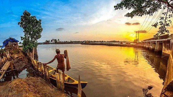 Two people standing on a wooden pier extending over a body of water at sunset or sunrise.