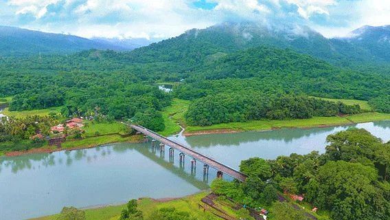 An aerial view of a green, hilly landscape with a river and a bridge.