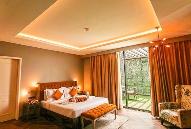 A bedroom featuring a king size bed with a bed bench, a couch, and an attached terrace - Polo Hotel Agartala