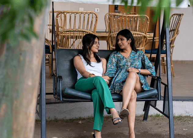 Two woman sitting in a chair facing each other.