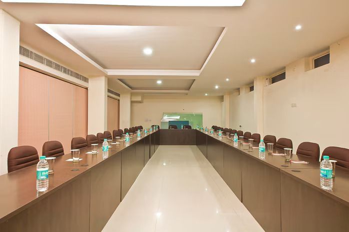 A wide-angle view of a U-shaped conference table arrangement in a well-lit room, ready for a meeting.