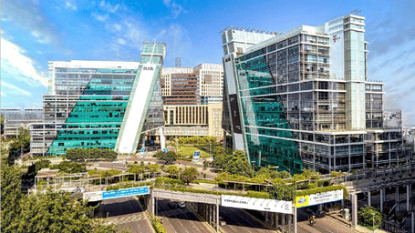 A corporate office campus in Gurgaon with tiered buildings, outdoor seating areas, and landscaped terraces.