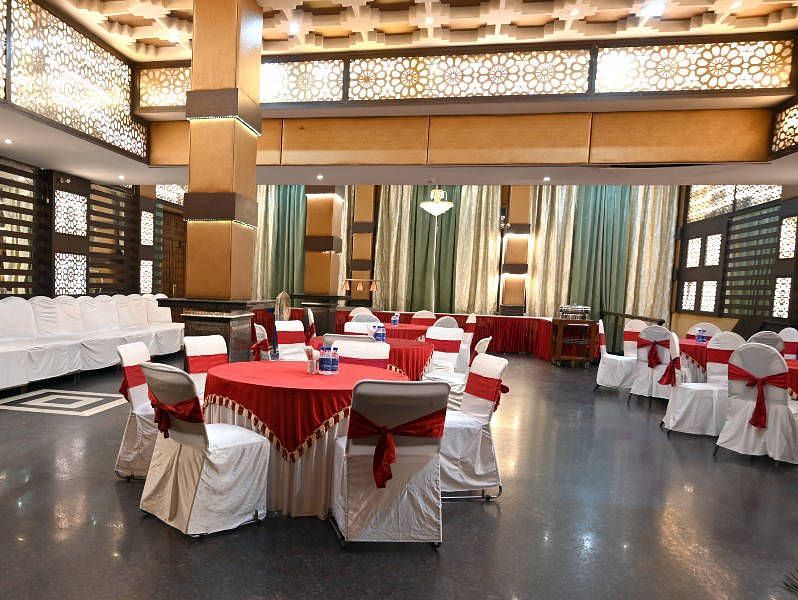 A beautiful conference hall with elegant lights in the ceiling featuring round tables set up all across the hall at Hotel Gold, Panipat.